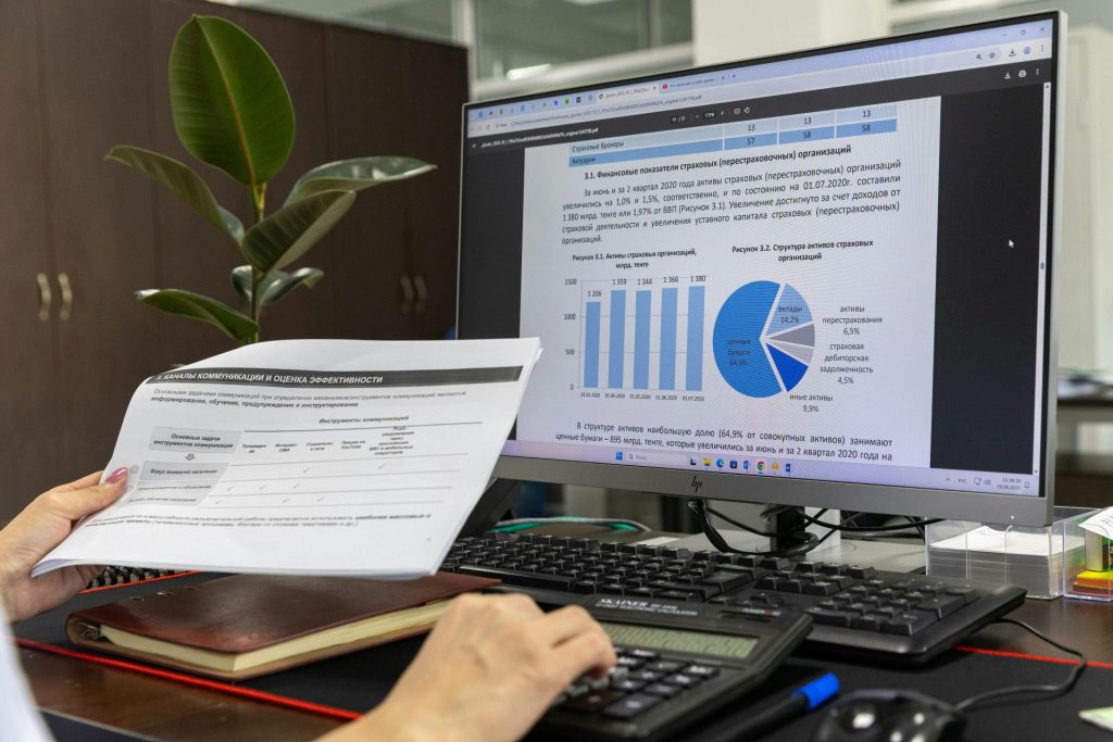 Eine Person analysiert Finanzdaten auf einem Computerbildschirm in einer Büroumgebung.