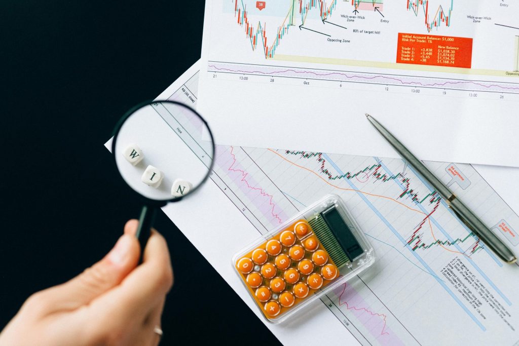 Eine Lupe hebt das Wort „WIN“ über Finanzdiagrammen hervor. Schärfen Sie Ihren Blick für die Unternehmensanalyse.