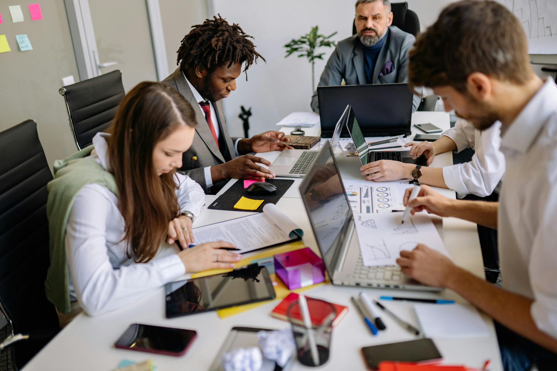 Ein Team von Fachleuten arbeitet in einem modernen Büro gemeinsam an einem Tisch und konzentriert sich dabei auf Projekte und Diskussionen.