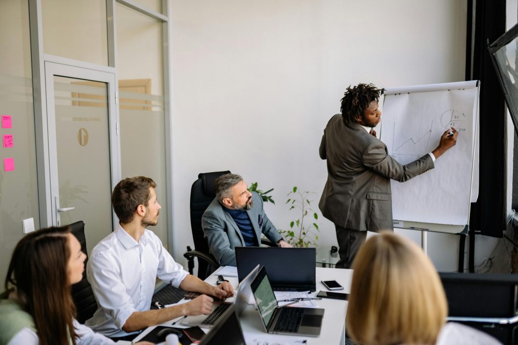 Ein vielfältiges Team in einem modernen Büro nimmt an einer strategischen Geschäftsbesprechung teil, die von einem Präsentator geleitet wird.